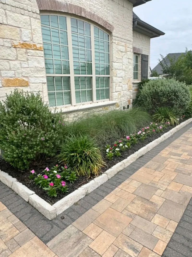 Stone flowerbed border beside a paver walkway