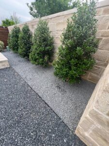 Metal edging separating contrasting gray rock beds with evergreen plants