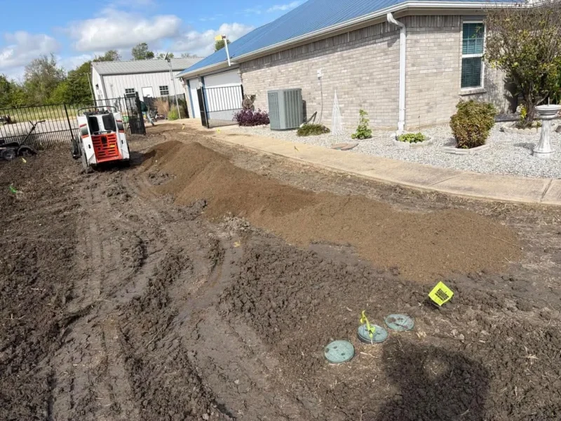 Soil preparation underway with equipment and material staged beside the walkway.